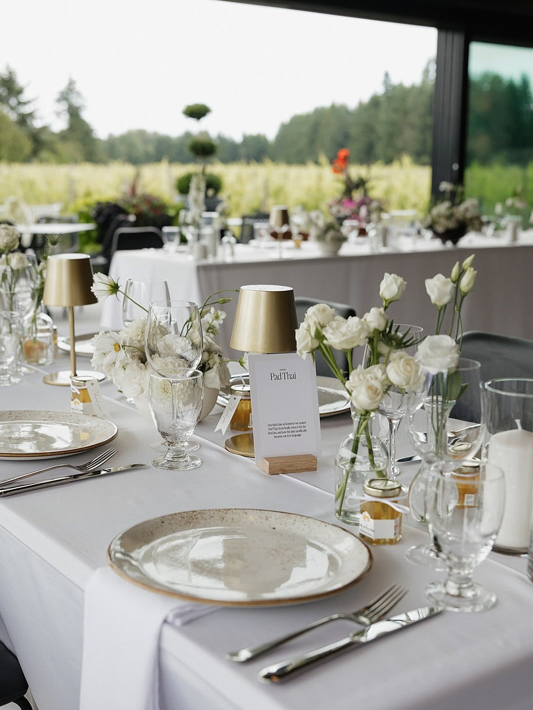 Elegant white tablescape with roses and gold lamps overlooking the vineyard
