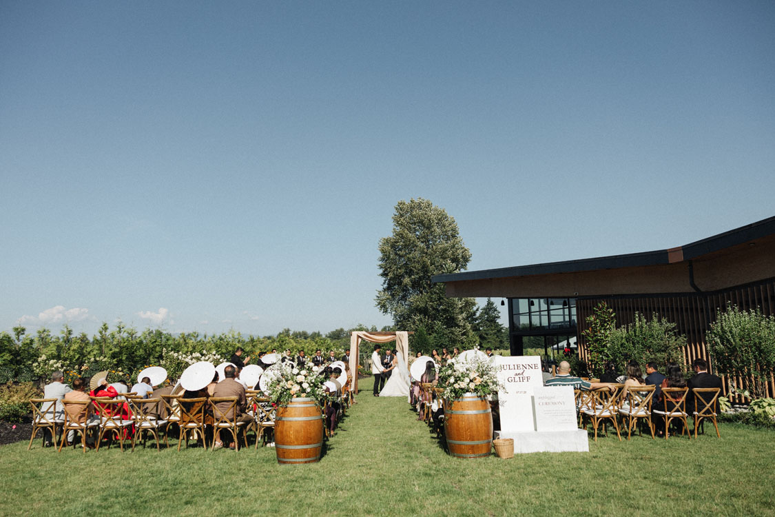 Outdoor wedding ceremony with wine barrel aisle markers