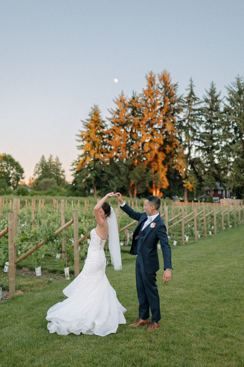 Couple twirling in the vineyard at dusk under the moon