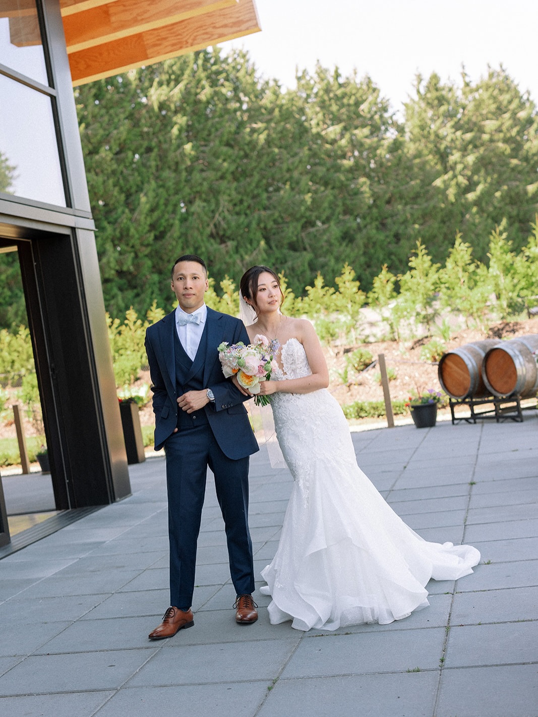 Bride and groom posing on the venue patio with wine barrels