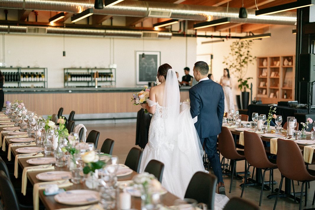 Bride and groom walking through the reception hall past long tables